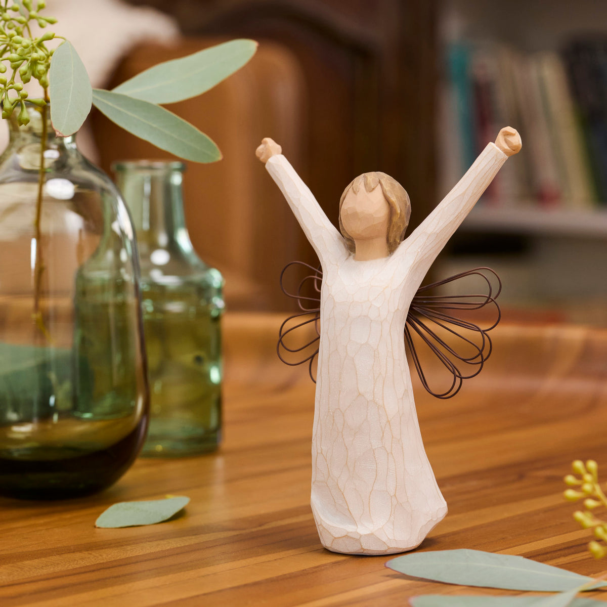 Willow Tree Courage, 6”h hand-painted standing resin angel figure in cream dress with wire wings, both arms upraised, on wood shelf with vase