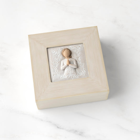 Cream square wood box with hinged lid, carving on lid of female in cream dress with hands in prayer position, surrounded by leaves and vines
