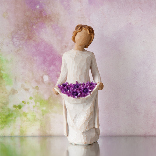 Willow Tree Simple Joys, 5.5”h hand-painted standing figure in cream dress, holding up skirt filled with purple daisies, in front of lavender painting