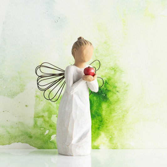 Willow Tree You're The Best!, 5.5”h hand-painted standing resin angel figure in cream dress with wire wings, holding red apple in outstretched hands, in front of green painting