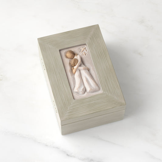 Light gray rectangular wood box with hinged lid, carving on lid of female and child embracing in cream dresses