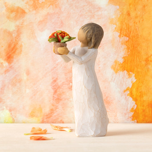 Willow Tree Little Things, 5.25”h hand-painted standing resin figure in cream dress, holding out terracotta pot with orange flowers, in front of orange painting