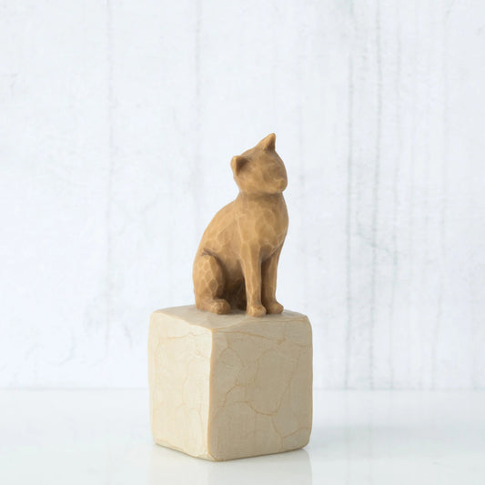 Golden cat figurine sitting on white rock