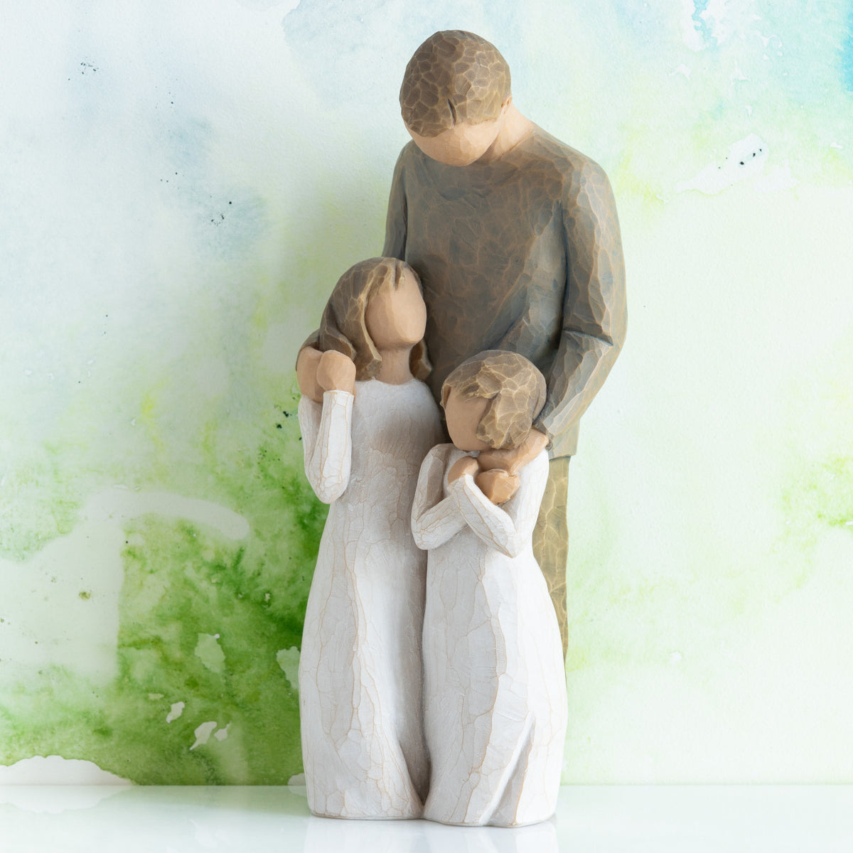 Willow Tree My Girls, 8"h hand-painted standing resin figure of father with arms around two young girls, all in neutral clothing, in front of green painting