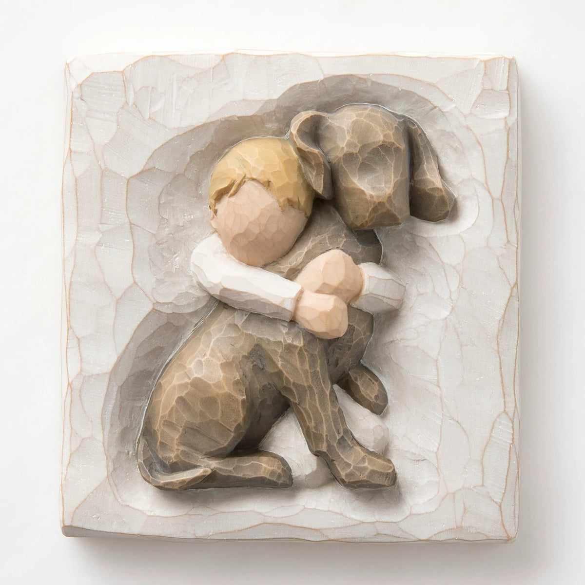 Close up of carved white square stone - in the middle is faceless young boy holding larger brown dog