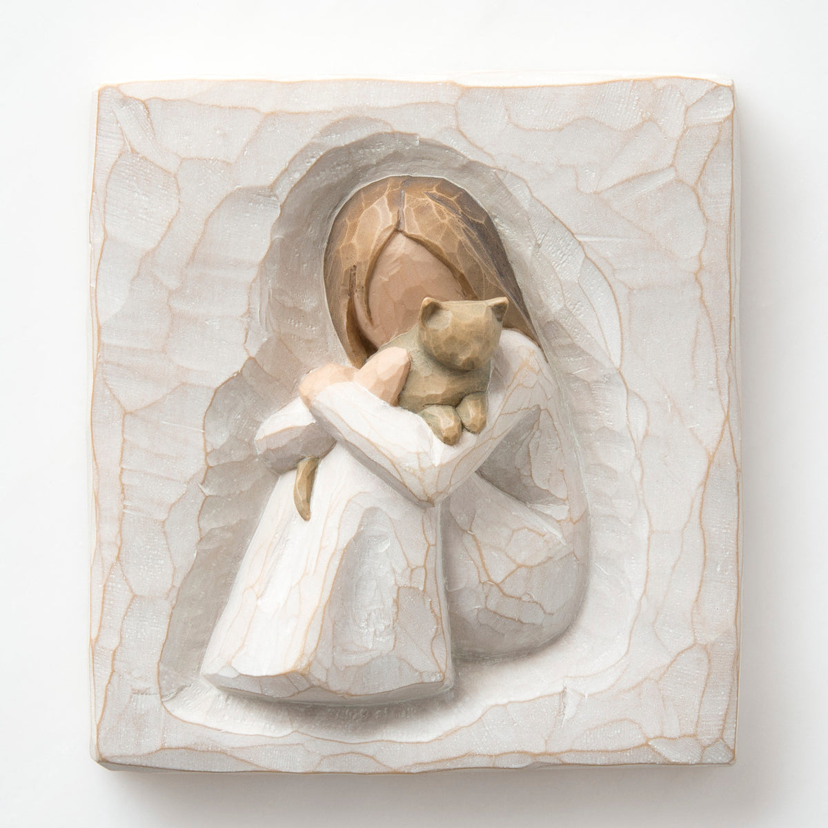 Close up of carved white square stone - in the middle is faceless young girl holding brown cat