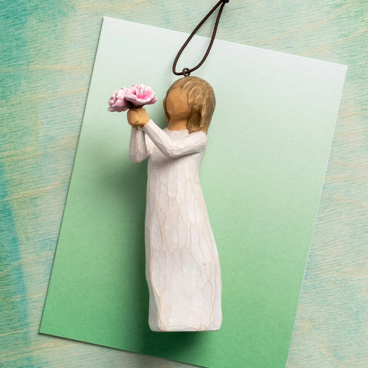 Willow Tree Thank You Ornament, 4”h hand-painted resin figure in cream dress, holding out bouquet of pink peonies, brown elastic cord, laying on green ombre painting
