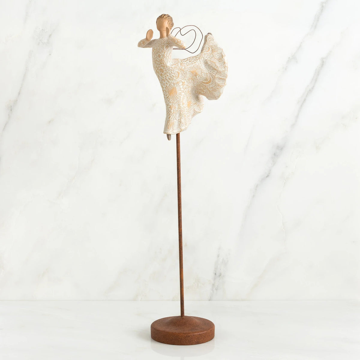 Far shot of angel figurine dressed in white dress dancing with arms and legs out - she is on a brown wooden stand
