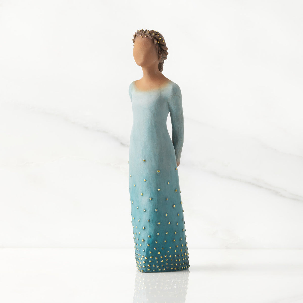 Front/left view: Darker-skin figure, arms clasped behind back, hair and deep blue ombré garment dotted with gold leaf