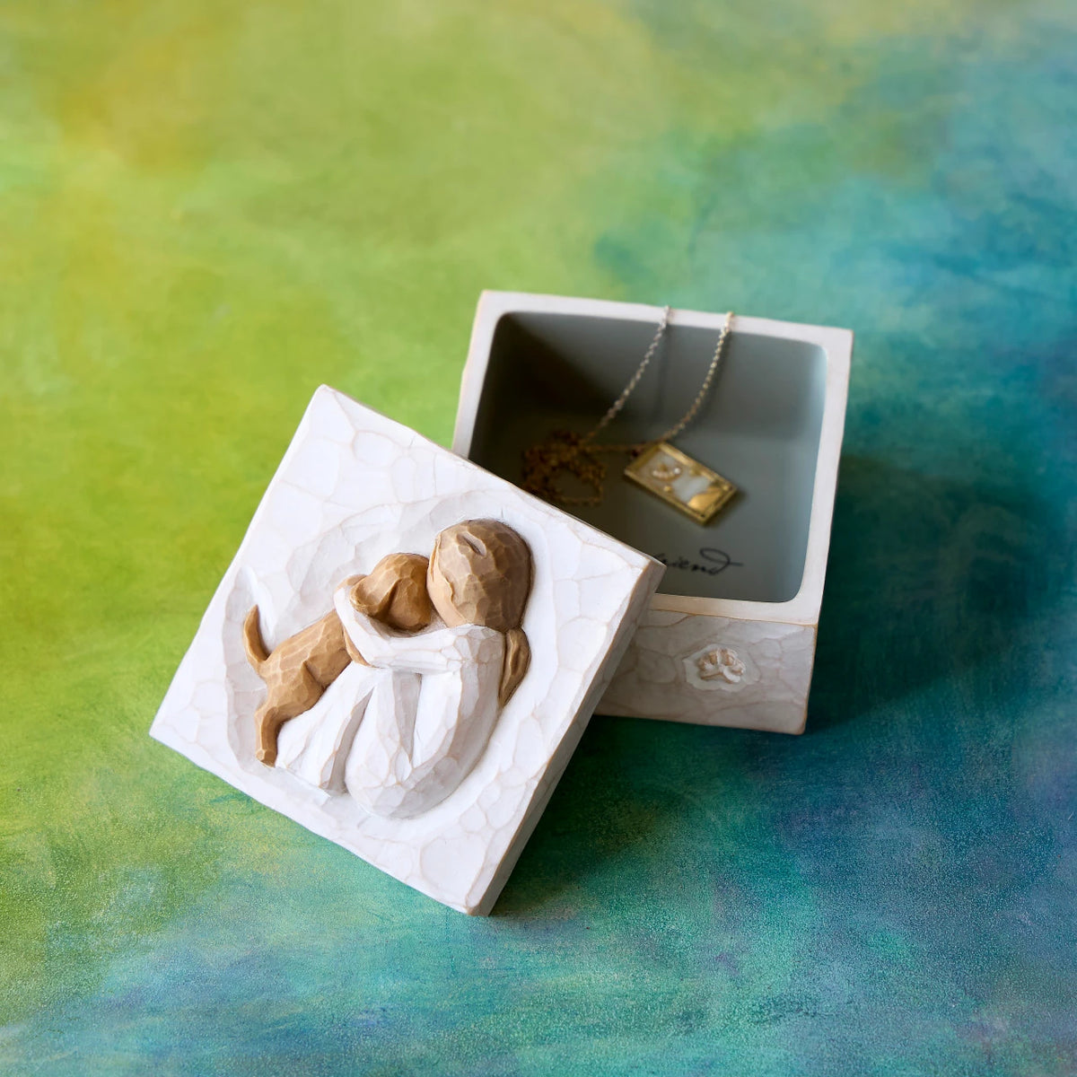 Willow Tree Friendship True Box, 3”sq x 2”h hand-painted resin box with removable lid off to one side, jewelry inside box. Lid has bas-relief carving of seated figure in cream dress, playing with yellow dog, inside of box has sentiment