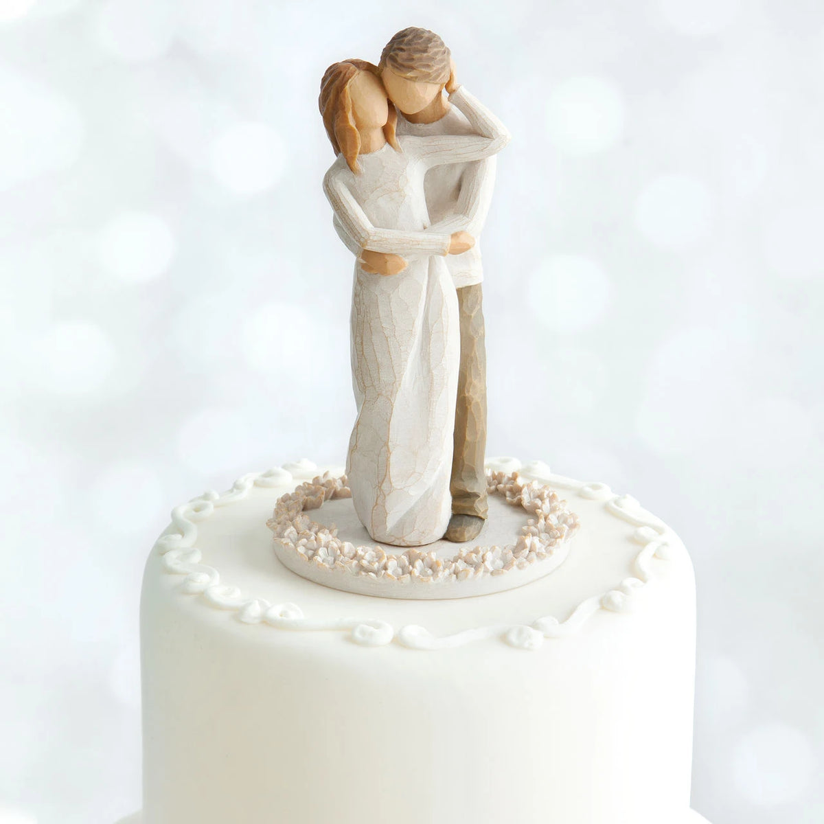 Willow Tree Together Cake Topper, 6”h hand-painted resin figure of couple, standing with arms around each other, dressed in neutral colors, affixed to 3.5" diameter food-safe base of carved white flowers