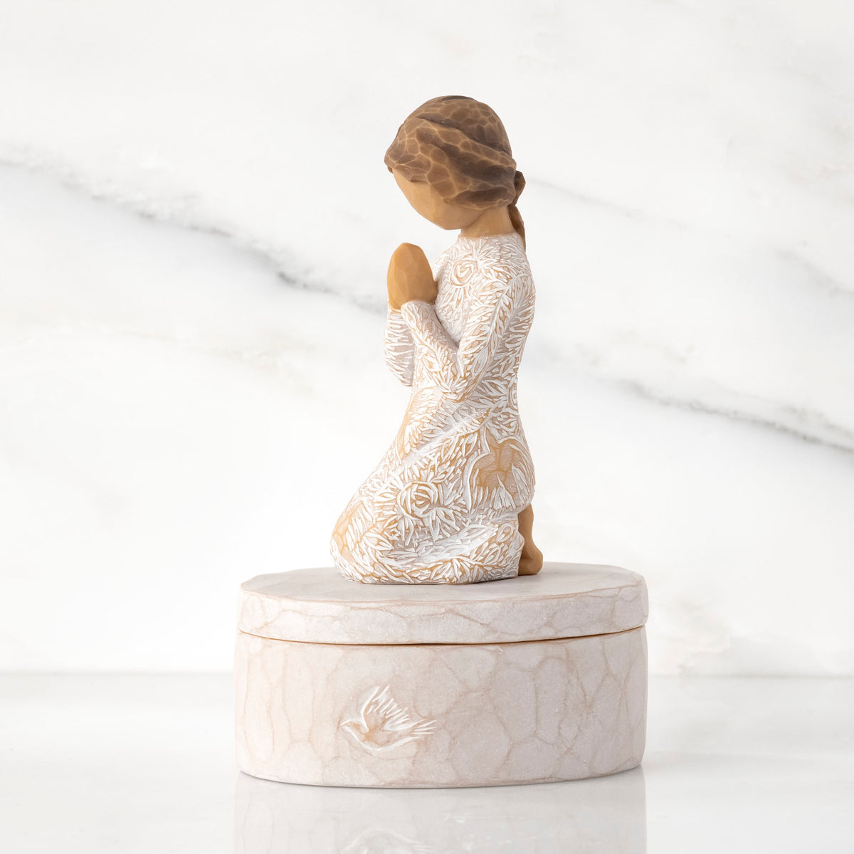 Left side: cream oval resin box, 3-D figure in prayer pose atop lid, in cream dress carved with birds and flowers