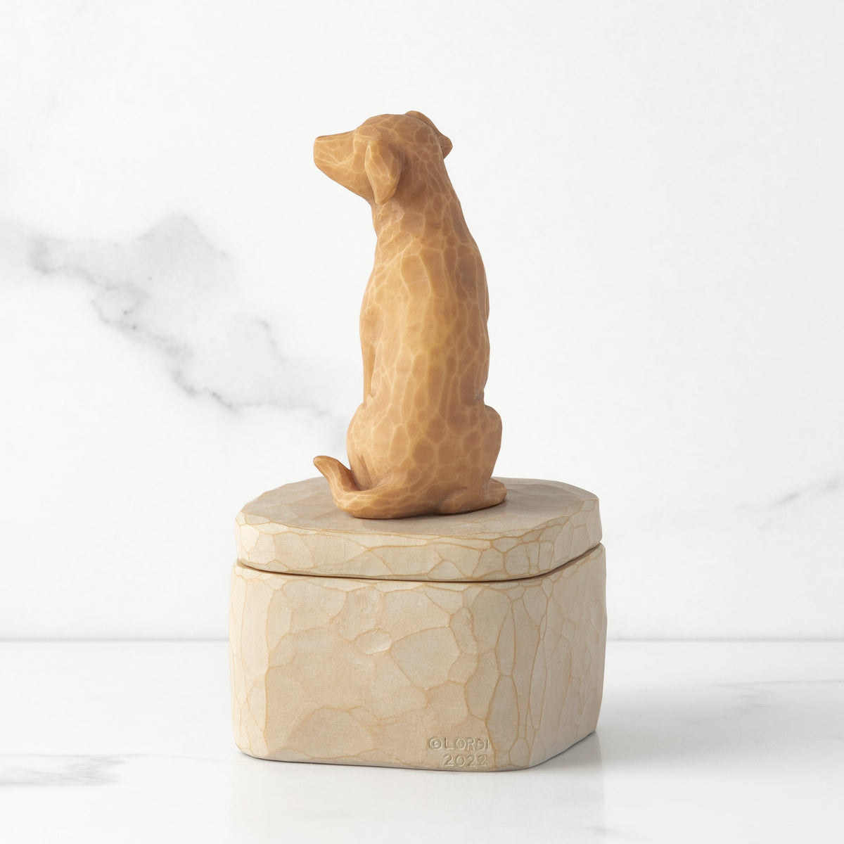 Back view: putty-colored square resin box with lid, 3-D figure of golden color dog atop lid