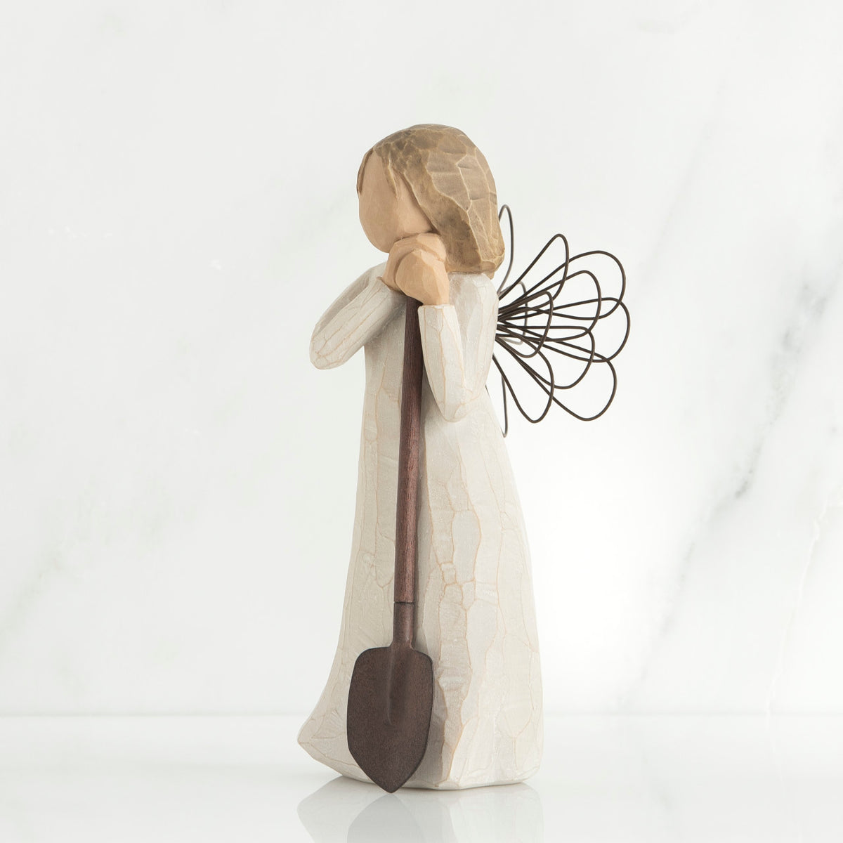 Young brunette girl figurine in white dress holding brown shovel
