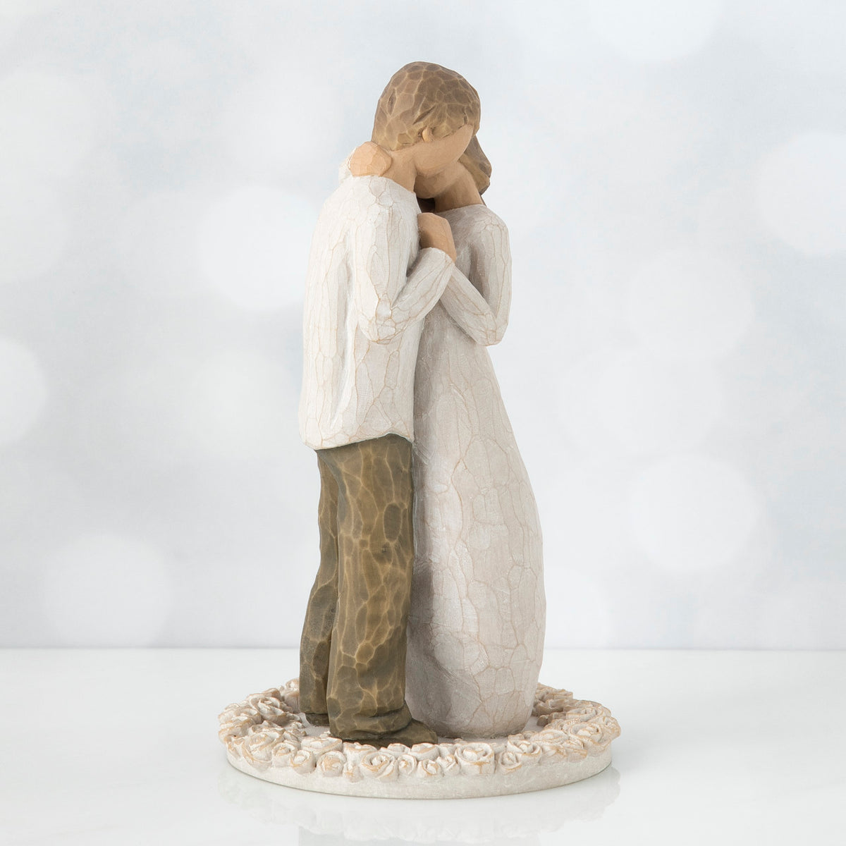 Man and woman figurine standing hugging another on round cream rose plaque