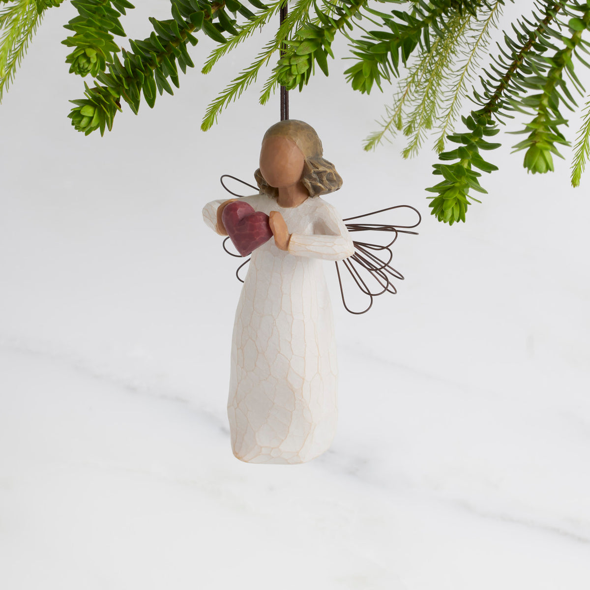 Facing left: Darker-skin Angel with wire wings holding red heart. Loop and hook attached in wings