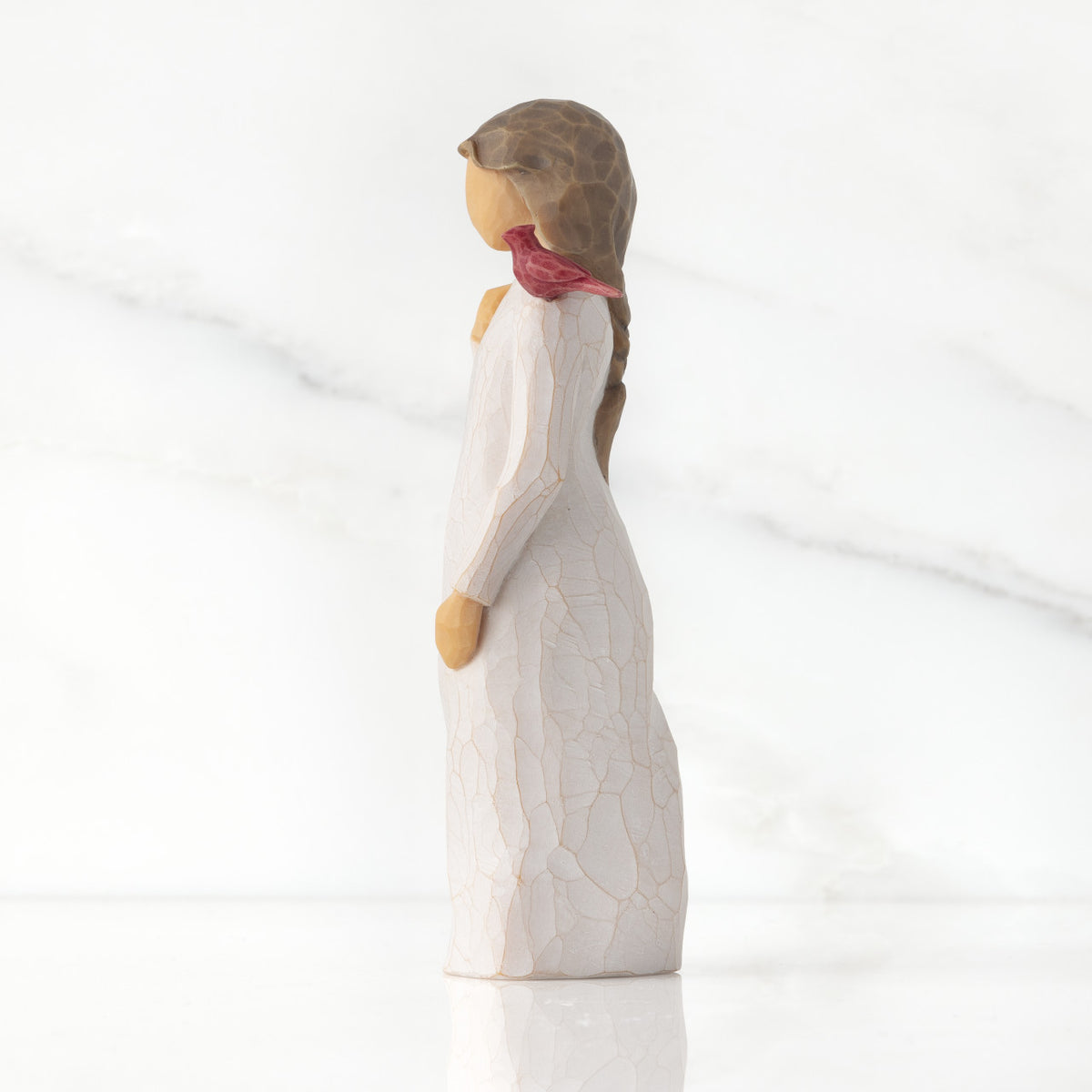 Left side of standing figure in cream dress with cardinal red bird perched on shoulder