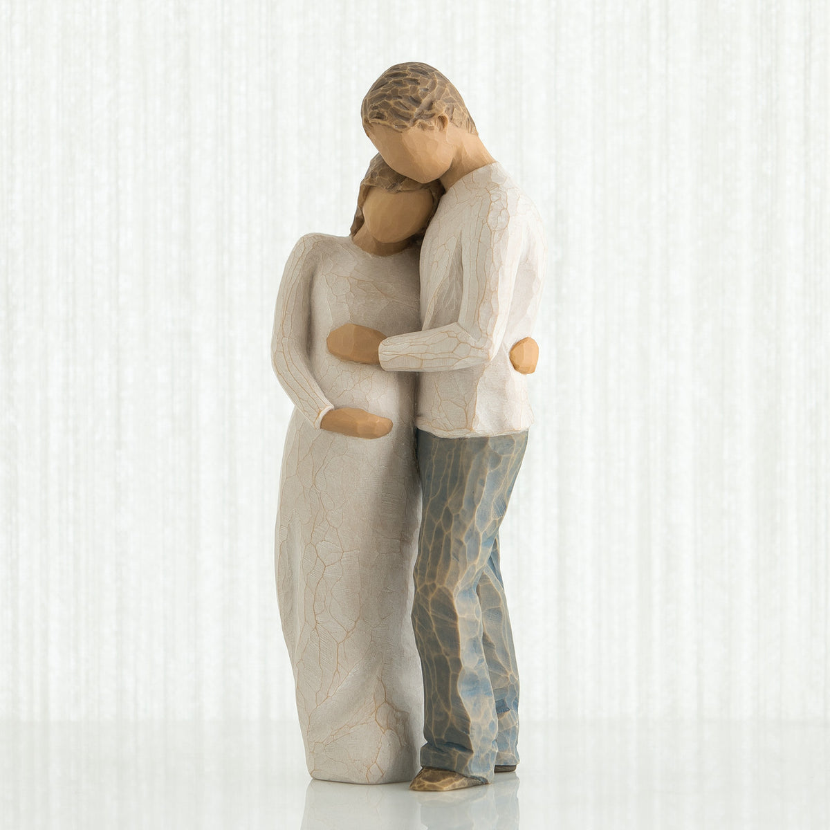 Man and woman figurines dressed in white holding the woman's stomach - white background