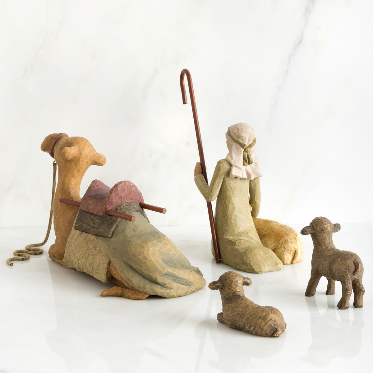Camel figurine, sheep figurines, and wise man figurine all laid out facing the back