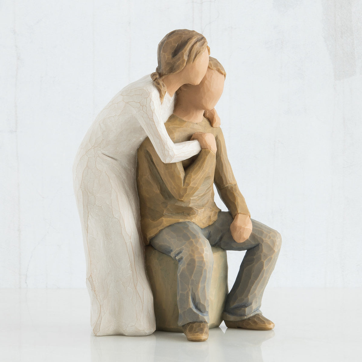 Close view of woman figurine in white dress with arms around man figurine in brown shirt
