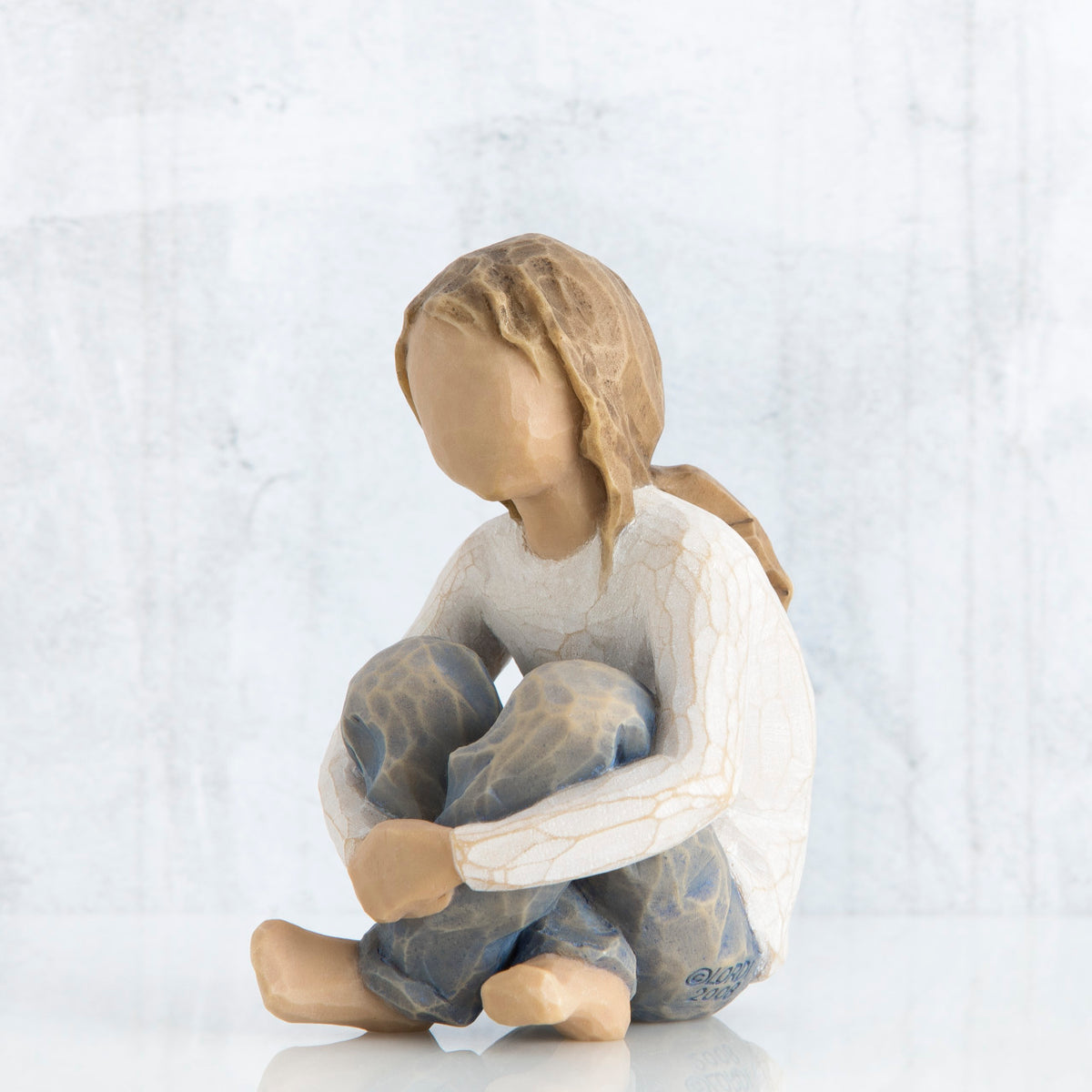 Front view of brunette girl figurine sitting down wearing white shirt and jeans