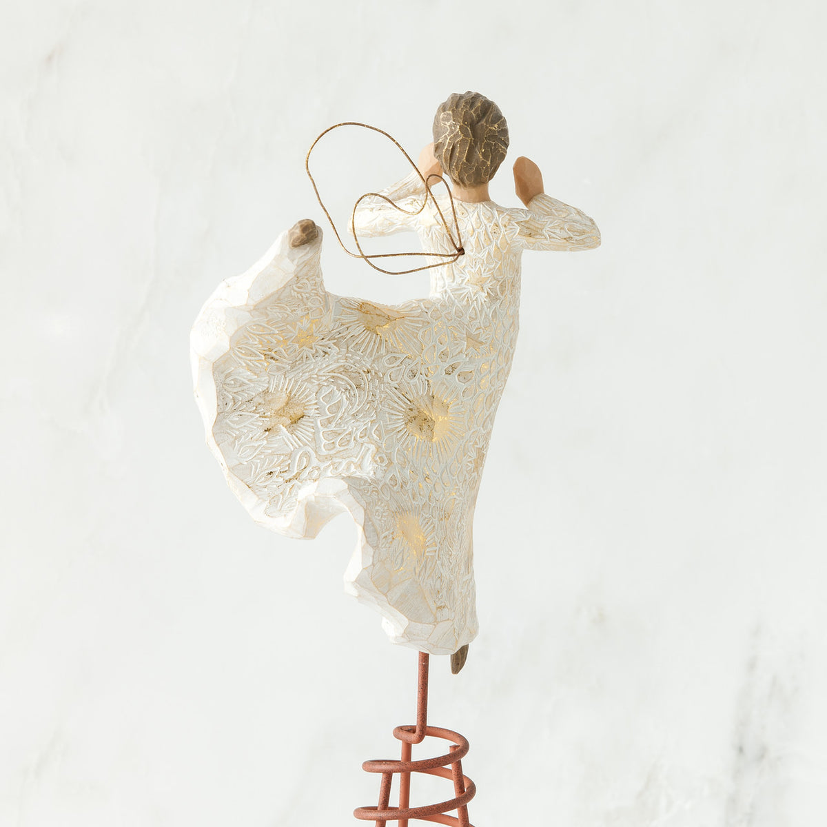 Brunette angel figurine facing away from camera in white dress, gold wings, and dancing on red stand with arms out