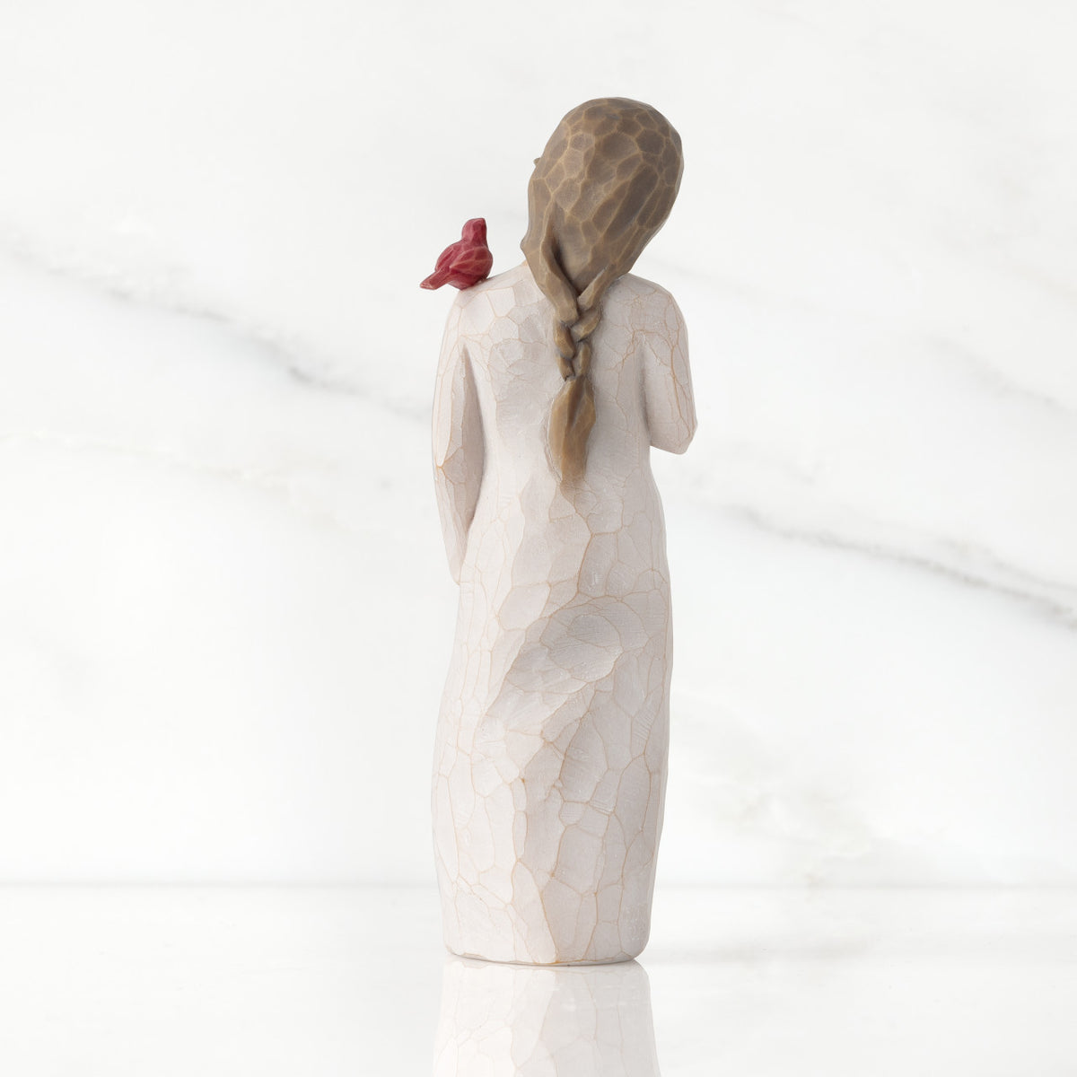 Back view of standing figure in cream dress with cardinal red bird perched on shoulder