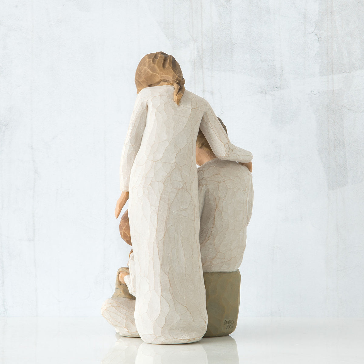 Back view of brunette woman in white dress standing up with arm over man figurine sitting down