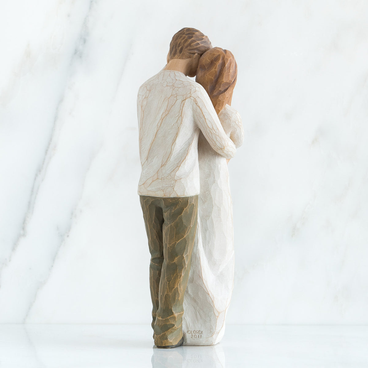 Back view of brunette couple in white hugging one another