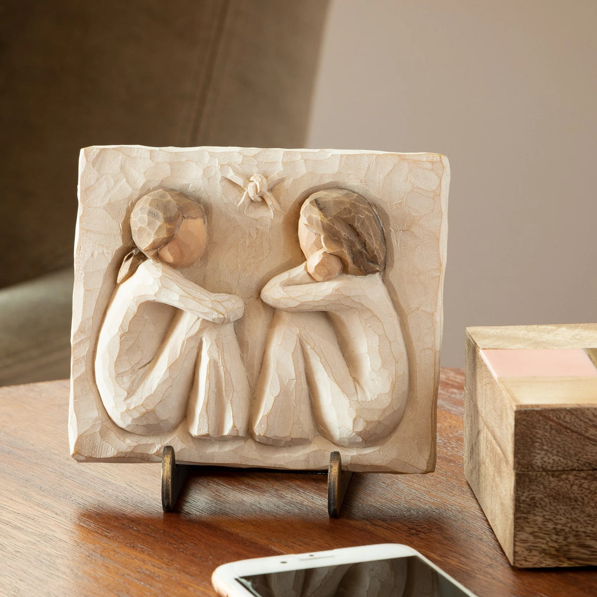 Willow Tree Friendship Plaque, 4”h x 4.75”w x .5”d hand-painted resin bas-relief carving of two seated figures in cream dresses, facing each other. Plaque displayed on Plaque Stand on side table