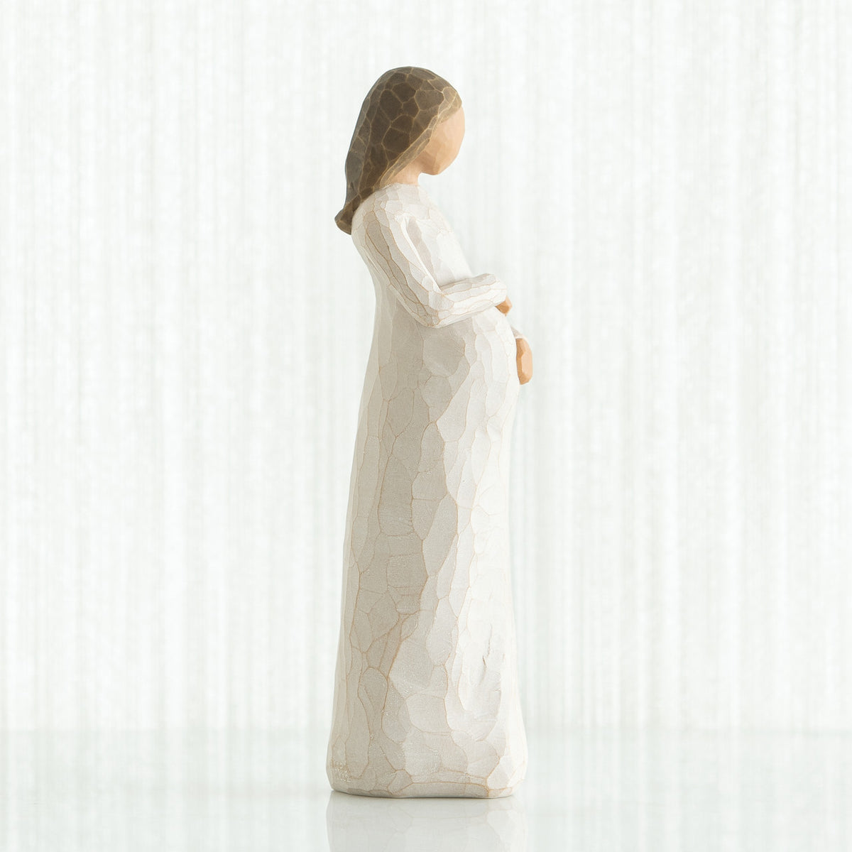 Side view of brunette girl figurine in white dress holding her stomach