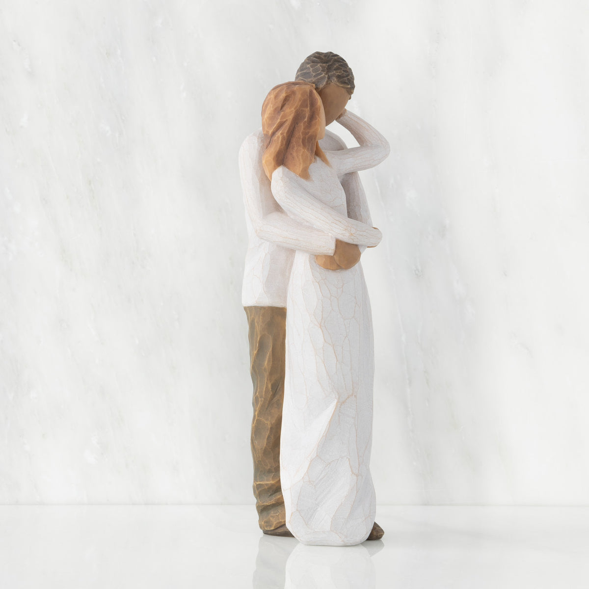 Right view of couple, standing with arms around each other. Woman has lighter skin and hair; man has darker skin and hair.