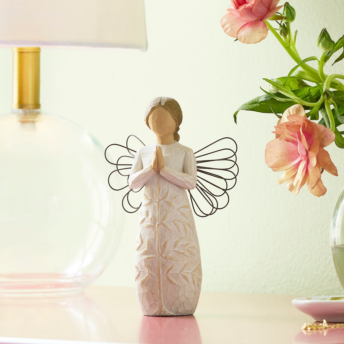 Willow Tree a tree, a prayer, 5.5”h hand-painted standing resin angel figure in cream dress with wire wings, hands in prayer position; tree carving on dress, on table with glass lamp