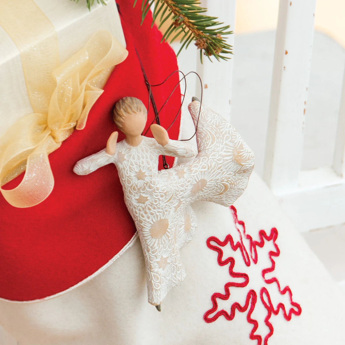 Willow Tree Song of Joy Ornament, 5”h hand-painted resin angel figure in ballet pose with hands raised to mouth, in cream dress carved with celestial symbols, with wire wings, brown elastic cord, hanging on Christmas stocking