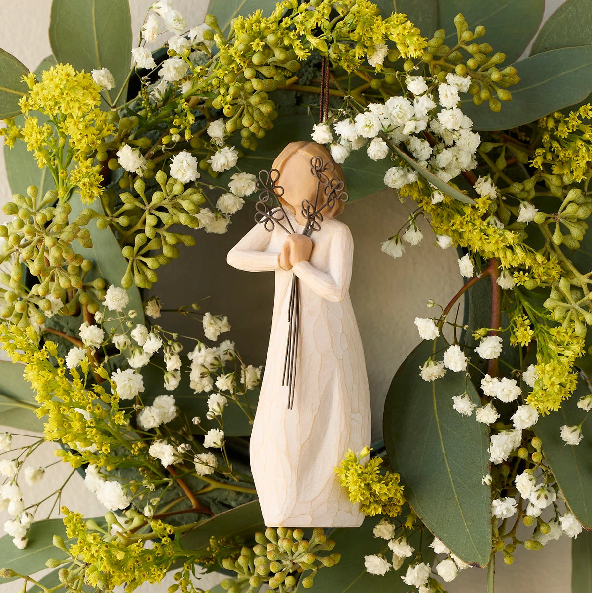 Willow Tree Friendship Ornament, 5.5"h hand-painted resin figure in cream dress holding wire flowers with long stems, brown elastic cord, hanging inside spring wreath