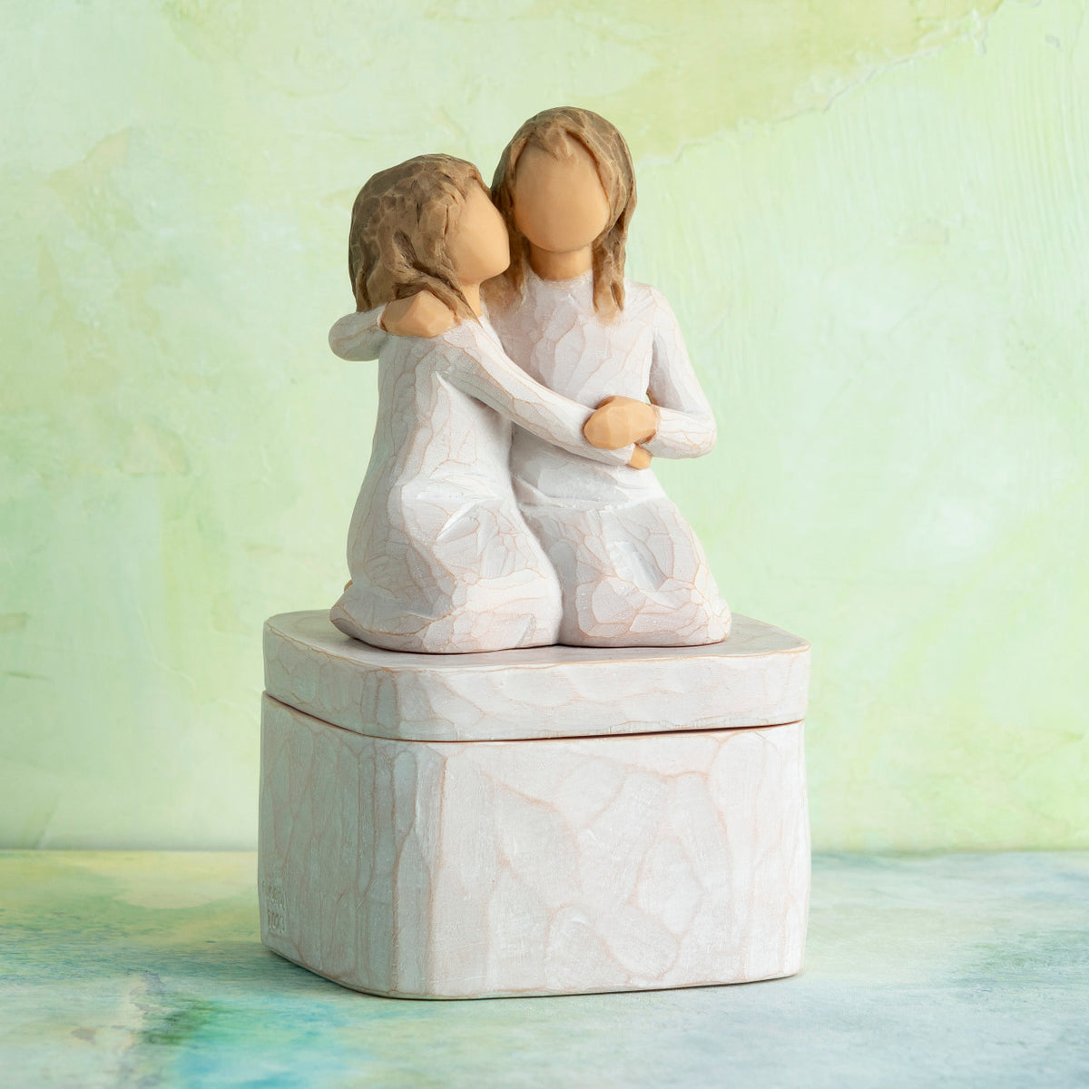 Willow Tree Sister mine Keepsake Box, 3"sq hand-painted resin box with 3.5”H figure of two kneeling girls in cream dresses, arms around each other, affixed to lid, in front of green painting
