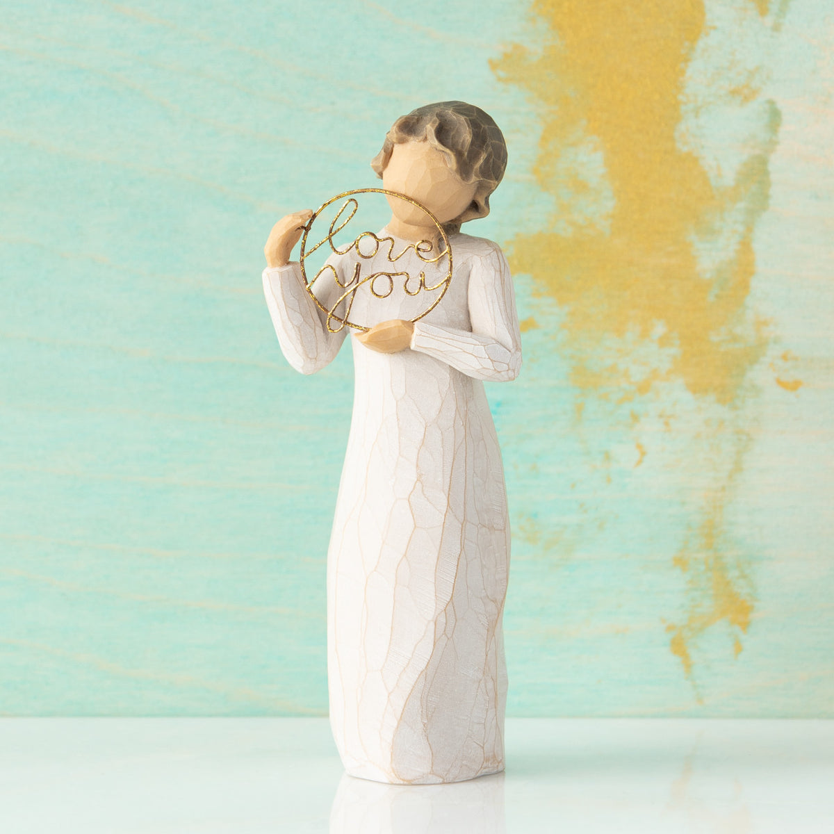 Willow Tree Love you, 5.5”h hand-painted standing resin figure in cream dress, holding gold wire circle with 'love you' inside, in front of mint and gold painting