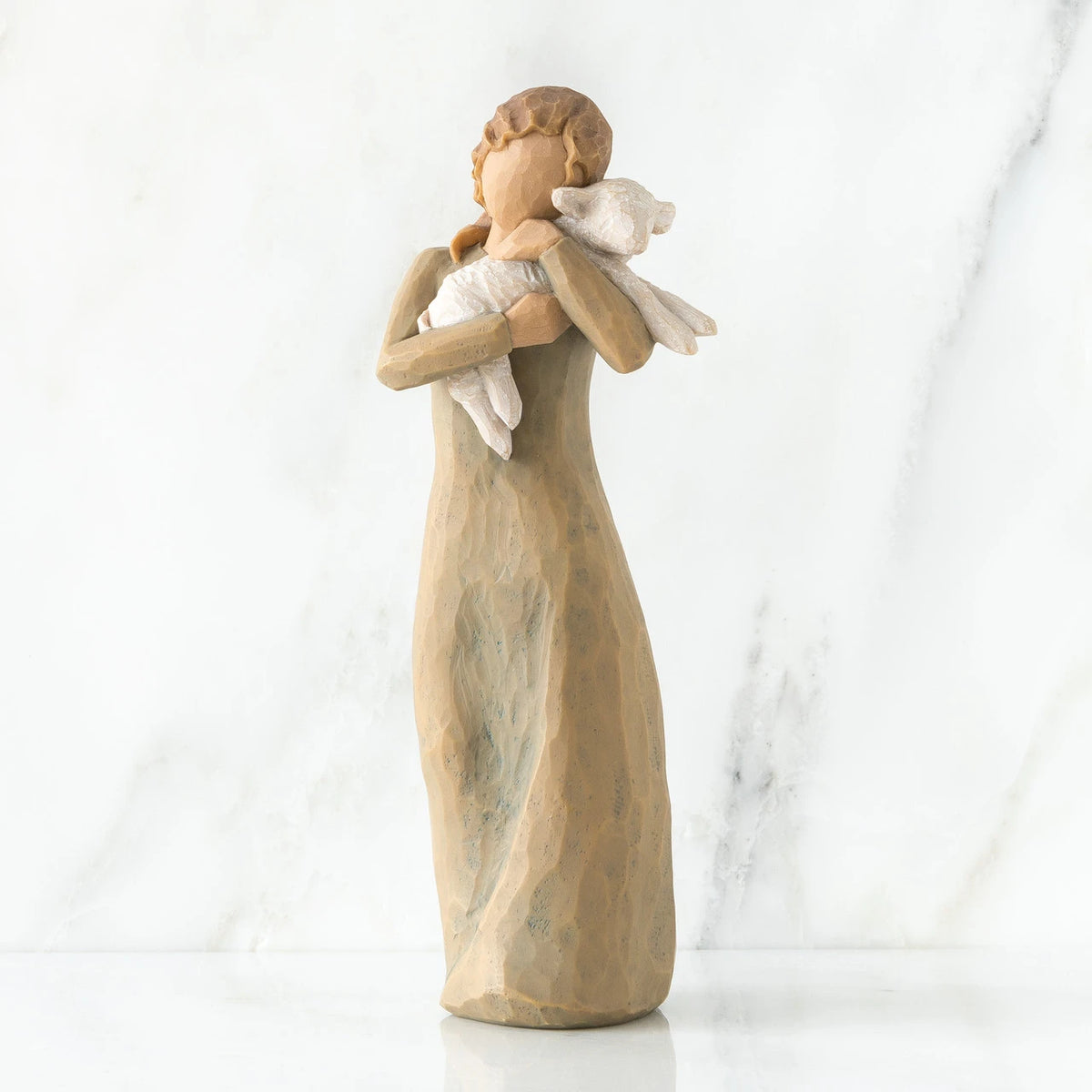 Faceless woman figurine standing wearing light tan dress holding white lamb in her arms