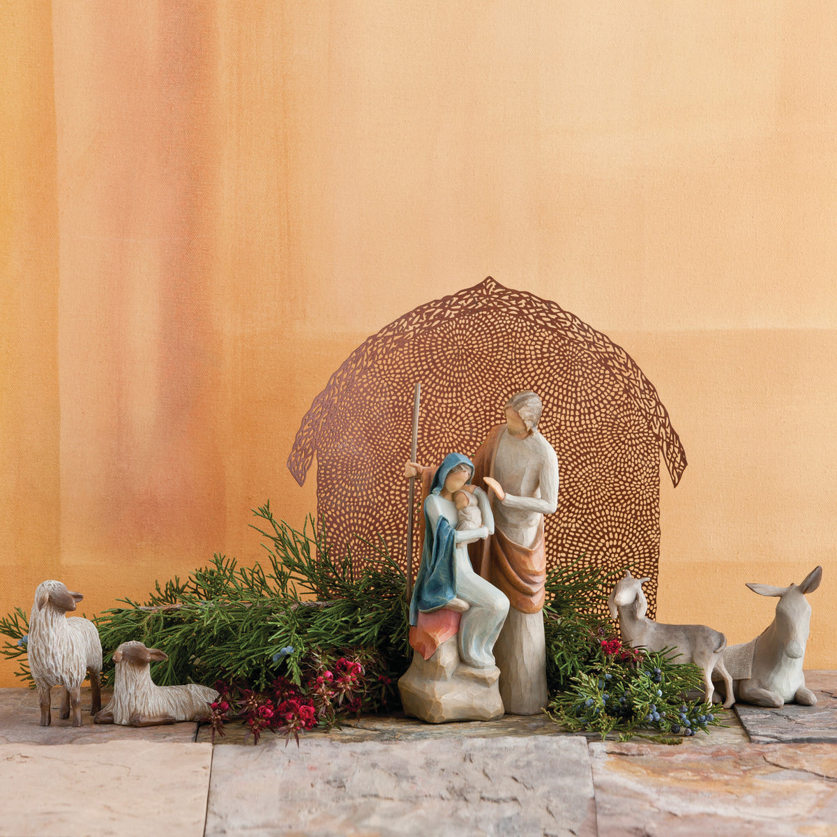 Far view of nativity scene figurines sitting on rock with brown barn in the background