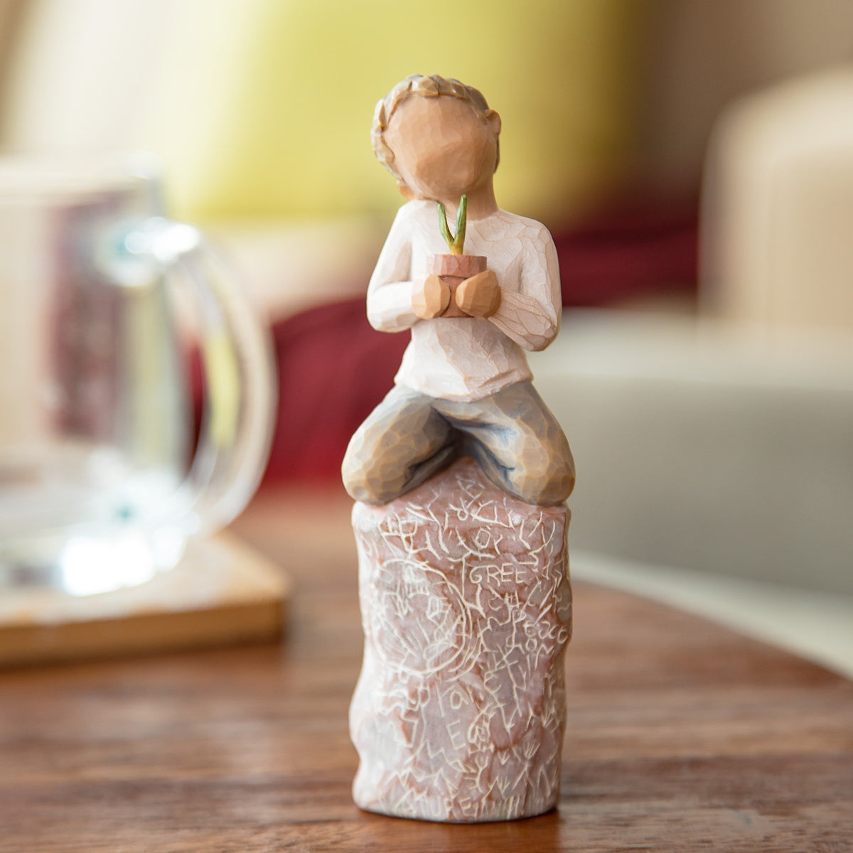 Willow Tree something special, 5.5”h hand-painted figure of small boy holding plant in pot, kneeling on tall rock etched with nature imagery, on desk