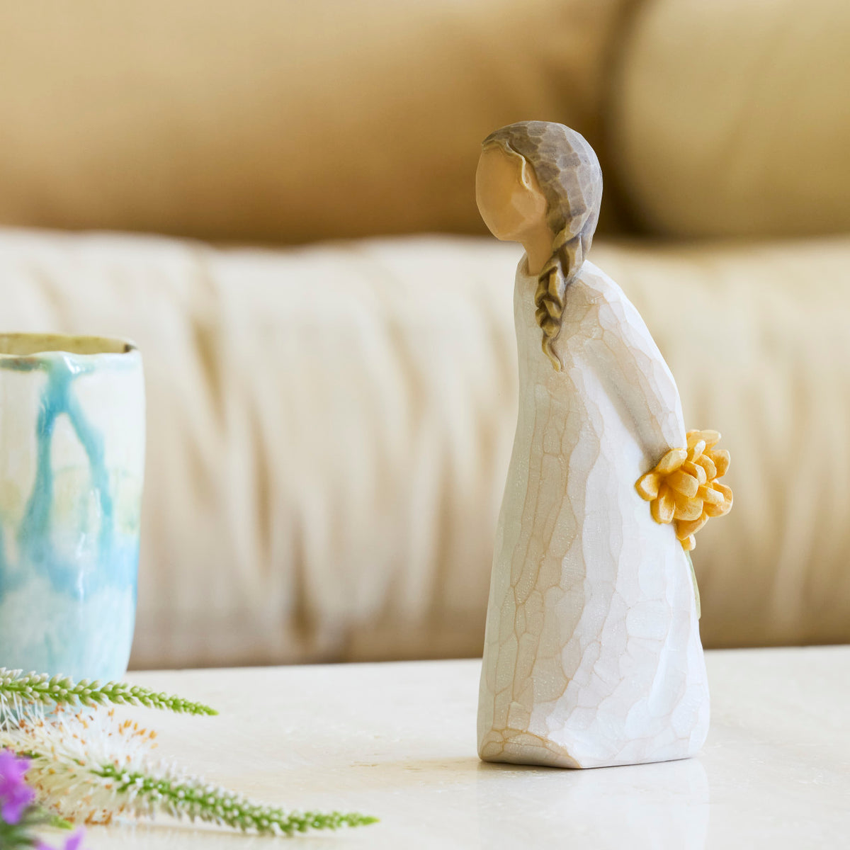 Willow Tree For You, 5”h hand-painted standing resin figure in cream dress, holding bouquet of orange flowers behind back, on bedroom table