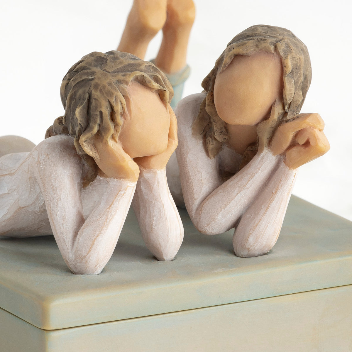 Front view of closed rectangular blue-gray resin box, detail of two girls’ faces, turned to show height of box sides